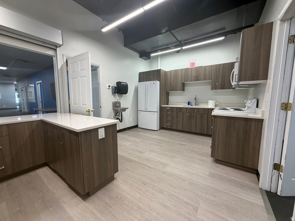 Spacious breakroom with light wood-finish flooring, white countertops, and wood-finish cabinetry
