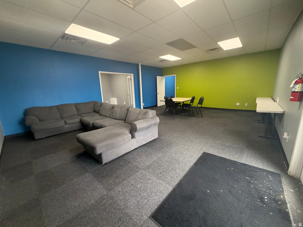 Spacious room featuring modular carpet flooring and a suspended acoustic ceiling with recessed lighting