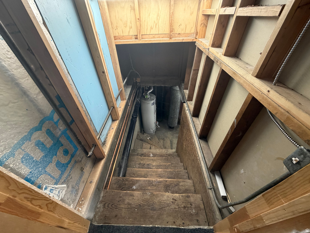 Utility space featuring exposed wood framing and a wooden staircase