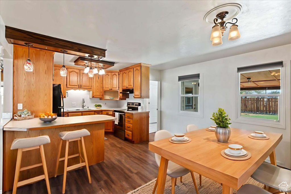 Kitchen with hanging light fixtures, light countertops, electric range, and a breakfast bar