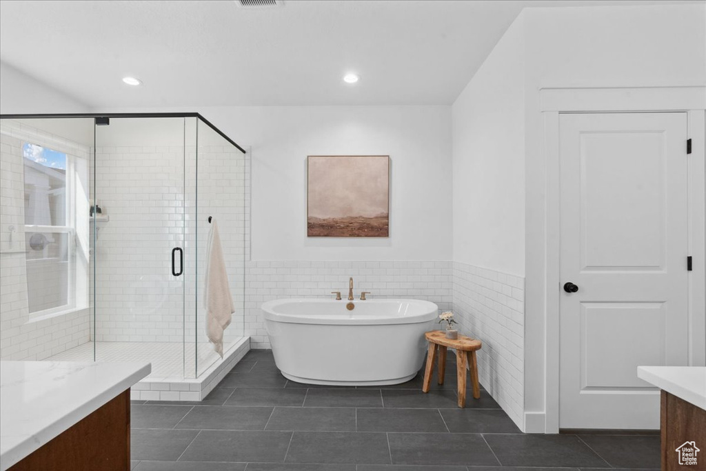 Full bath featuring vanity, a freestanding bath, wainscoting, tile walls, and a stall shower