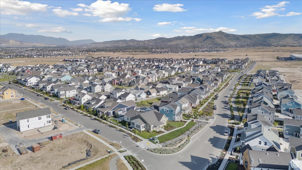 Aerial view of property and surrounding area featuring nearby suburban area and a mountain backdrop