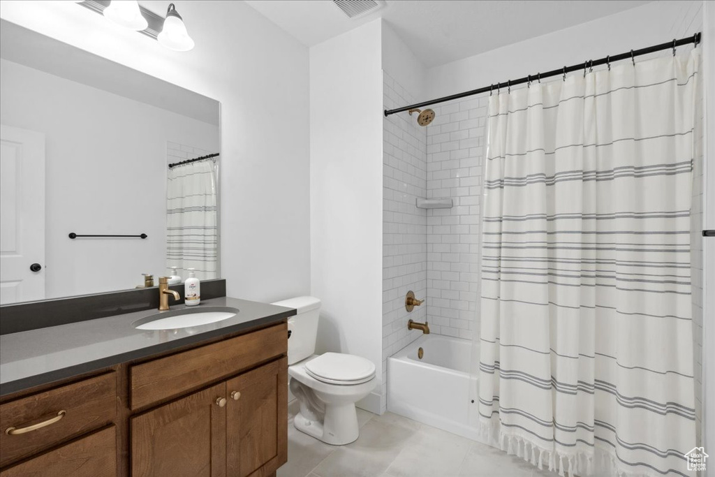 Full bathroom featuring vanity, shower / bath combo with shower curtain, and light tile patterned flooring