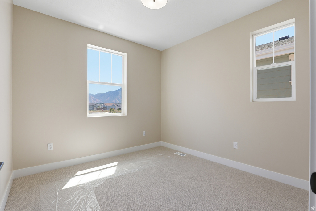 Bright room featuring two windows, neutral carpet, and light-toned walls