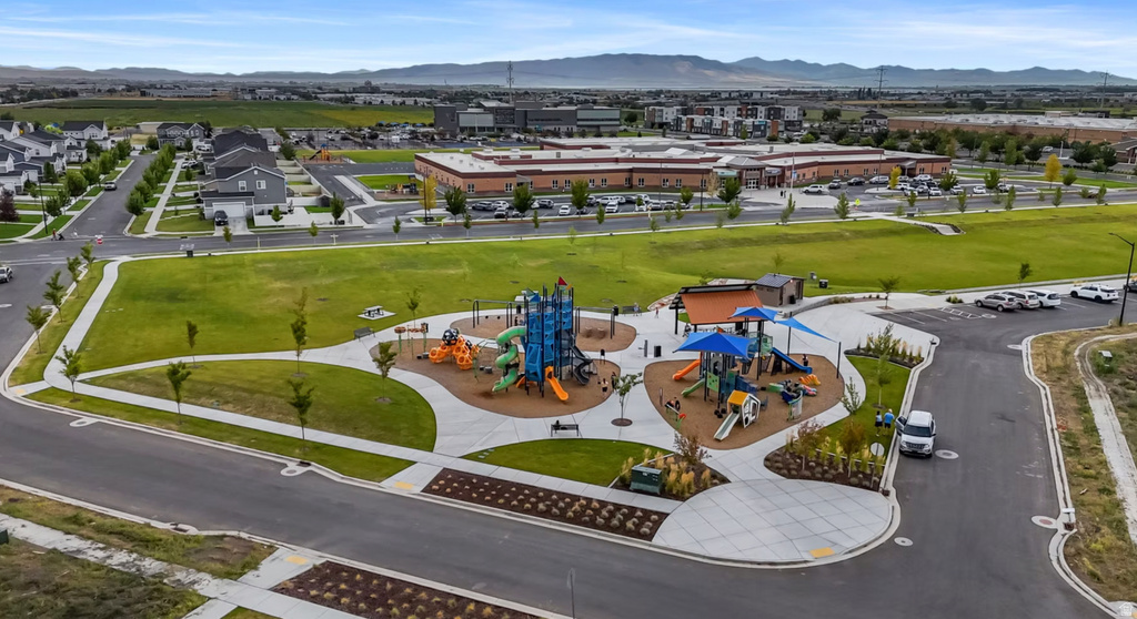 Community park featuring multiple play structures with slides and climbing elements, shaded seating areas, and expansive green space