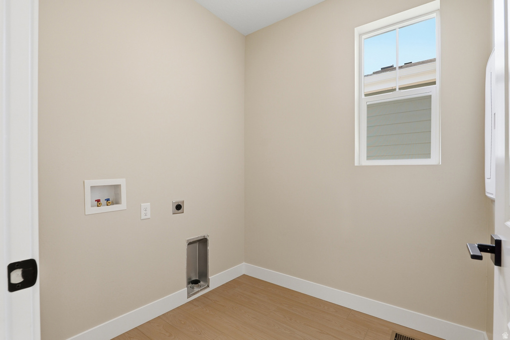 Dedicated utility space featuring light neutral walls and wood-finish flooring
