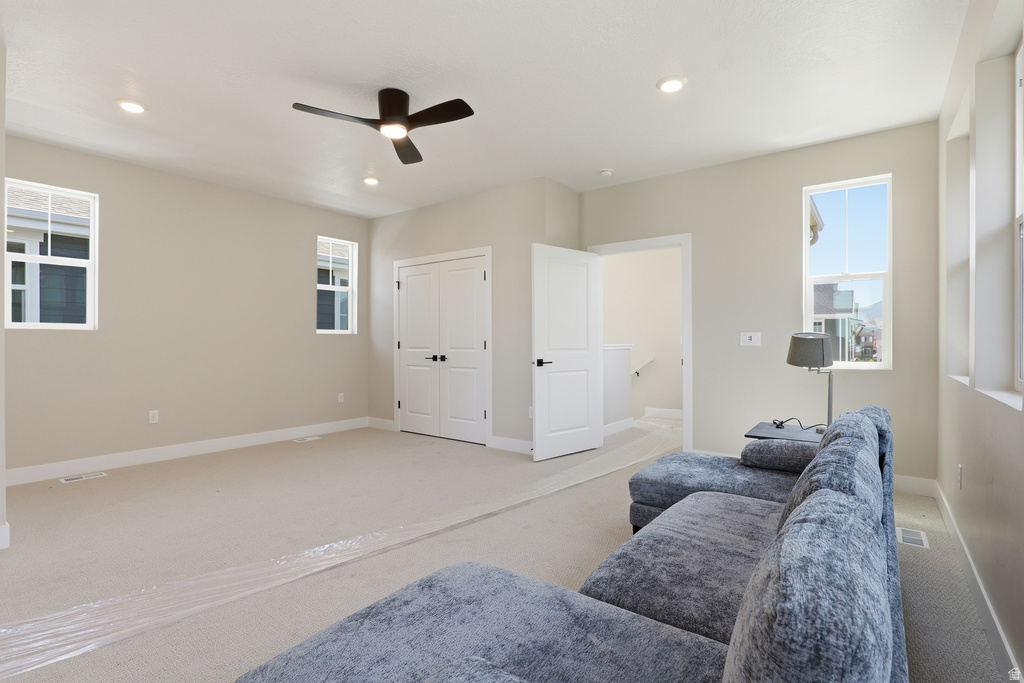 Spacious room featuring neutral carpeting, recessed lighting, and a dark-toned ceiling fan