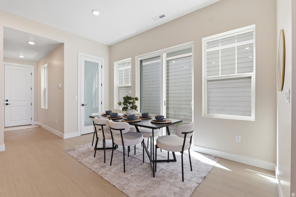 Spacious dining area featuring wood-finish flooring, recessed lighting, and a glass-paneled door
