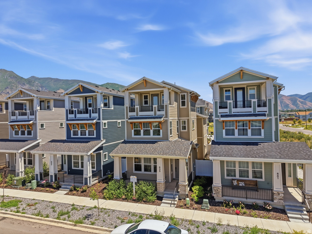 Multi-story residence featuring a covered front porch with stone accents, a second-story balcony with metal railing, and horizontal siding
