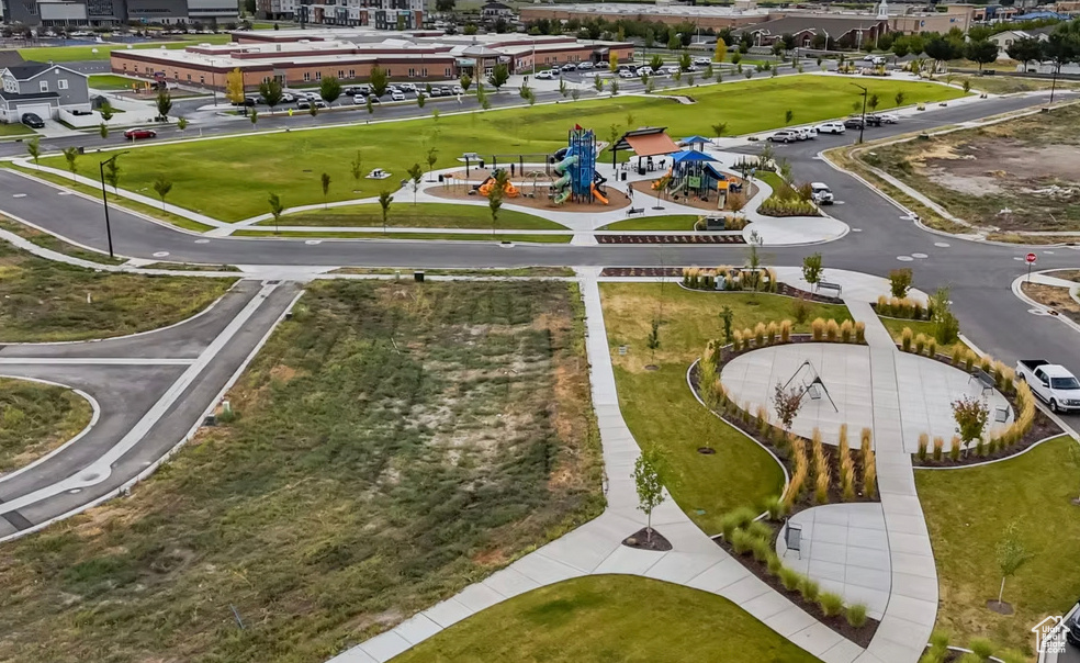 Community park featuring multiple playgrounds, expansive green spaces, paved pathways, and surrounding residential development