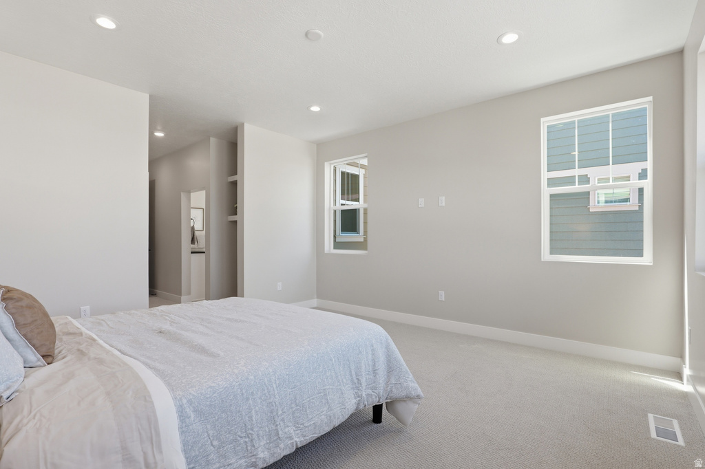Carpeted interior space featuring multiple windows, recessed lighting, and an alcove with built-in shelving