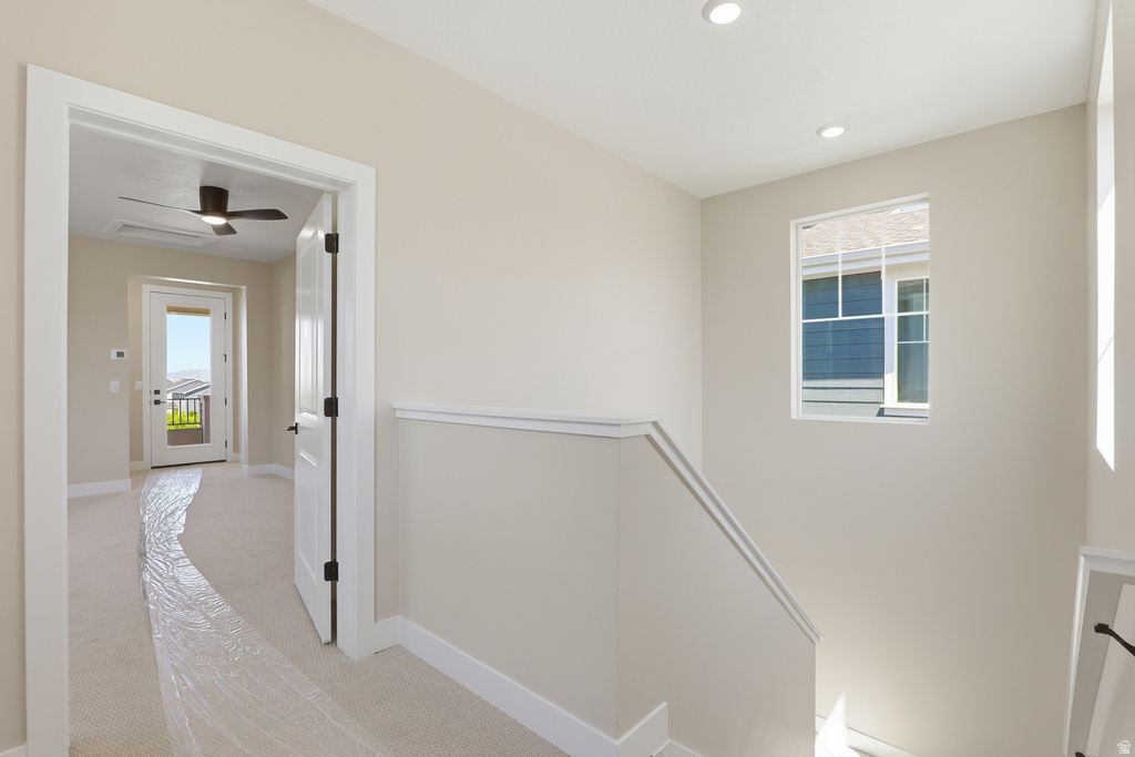 Upper landing featuring a window with white trim, recessed lighting, and a white balustrade