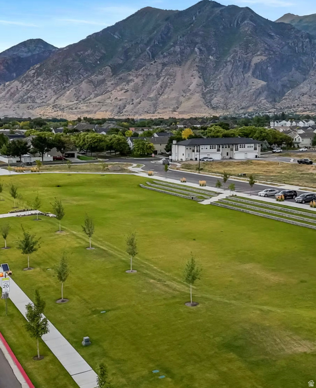 Expansive green space featuring a manicured lawn, established landscaping, and paved pedestrian pathways