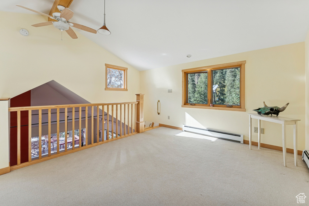 Carpeted empty room with lofted ceiling, a baseboard radiator, and a ceiling fan