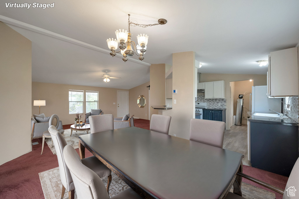 Dining area featuring a chandelier, lofted ceiling, ceiling fan, and wood finished floors