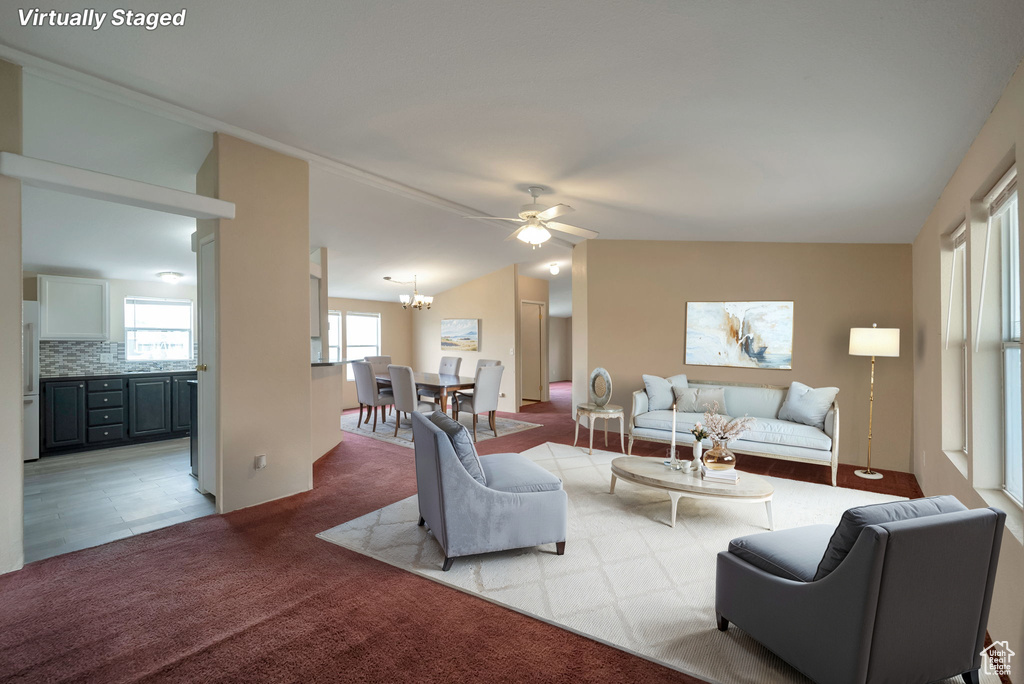 Living room featuring carpet flooring, ceiling fan, a chandelier, and lofted ceiling