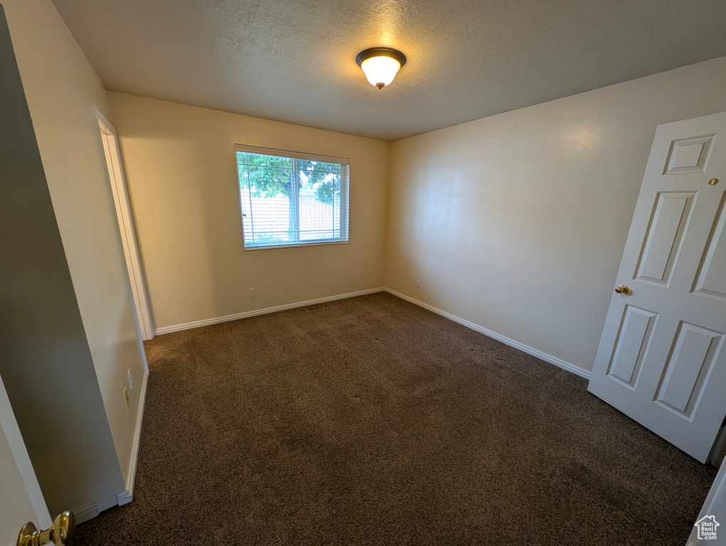 Spare room with dark colored carpet and a textured ceiling