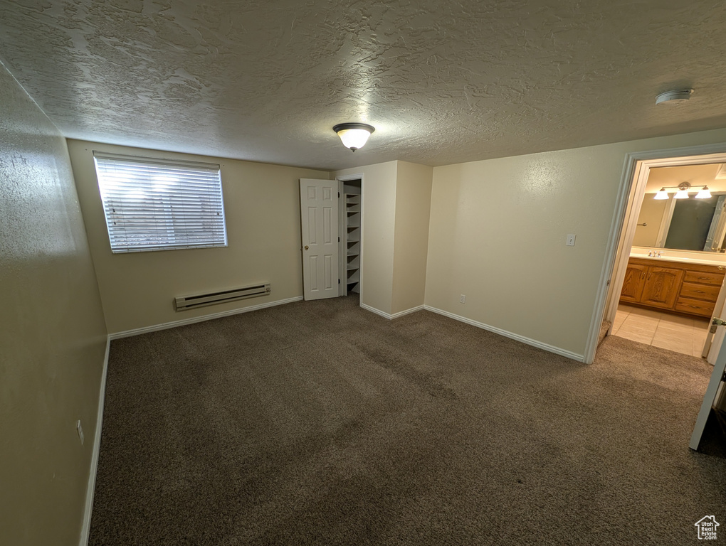 Unfurnished bedroom with carpet flooring, a textured ceiling, and a baseboard heating unit