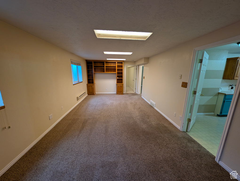 Empty room featuring light carpet, a textured ceiling, and built in shelves