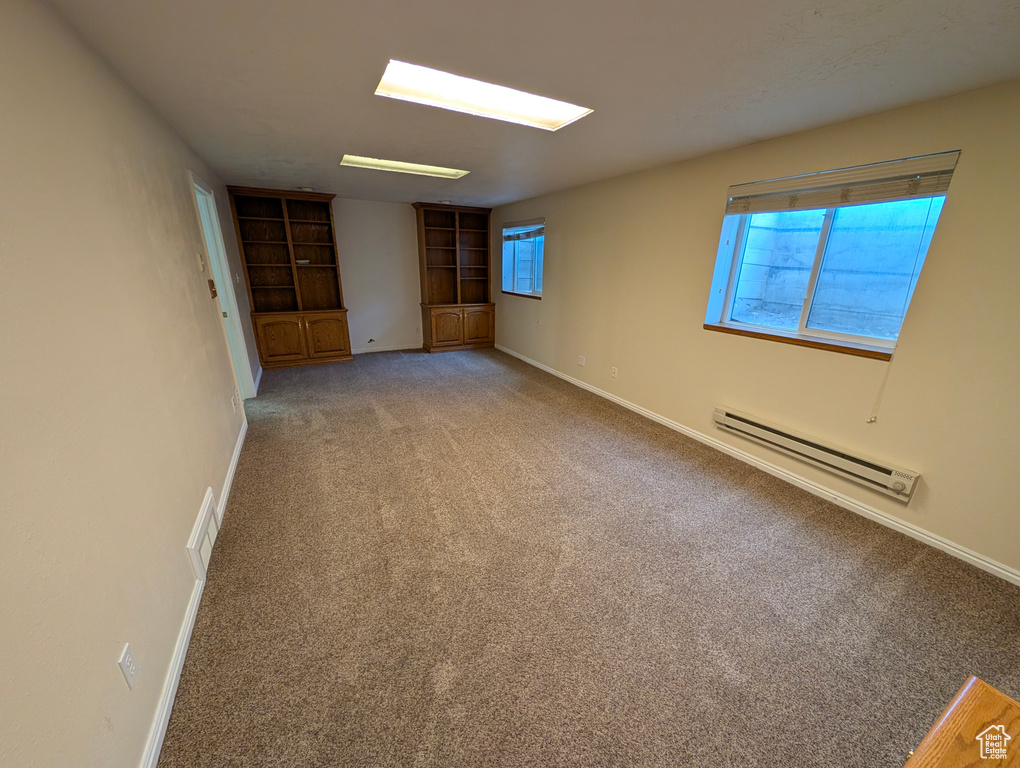 Unfurnished room with light carpet, a baseboard radiator, and built in features