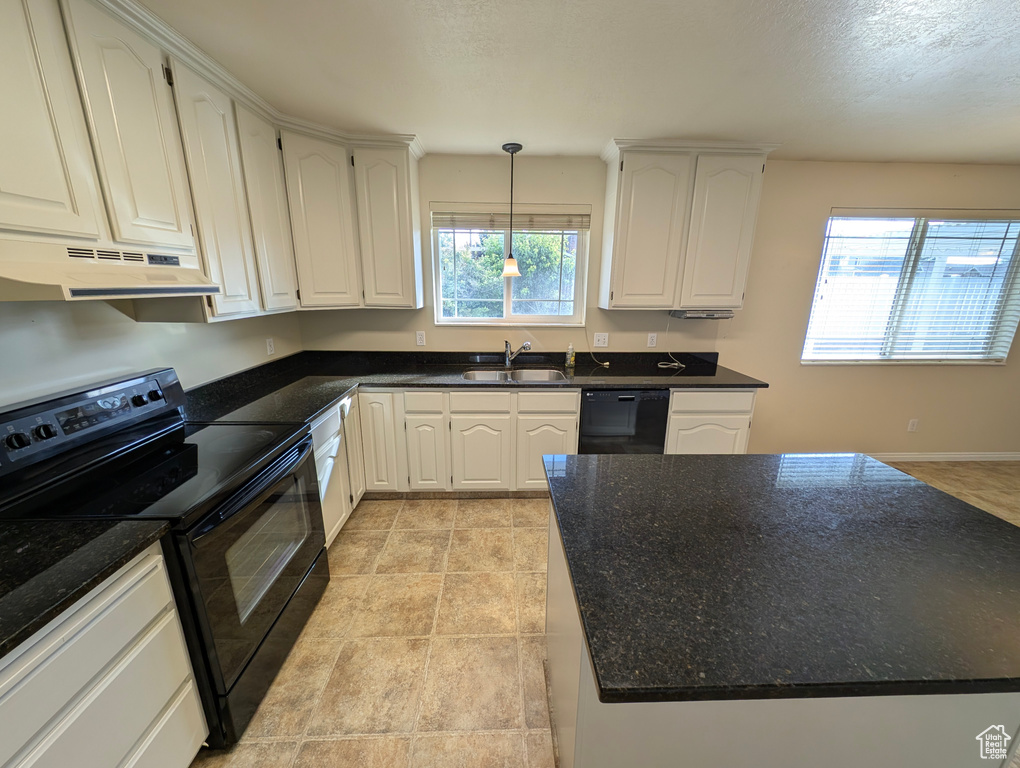 Kitchen featuring black appliances, hanging light fixtures, white cabinets, under cabinet range hood, and a center island