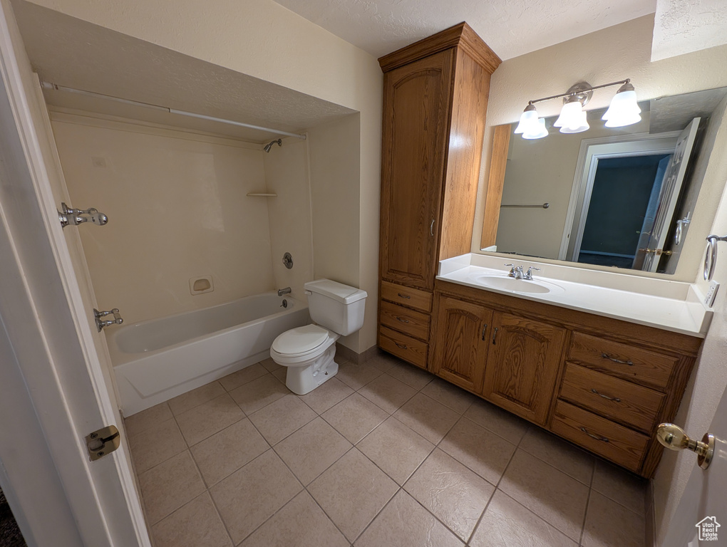 Full bathroom with light tile patterned floors, bathtub / shower combination, vanity, and a textured ceiling