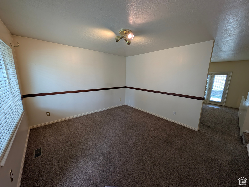 Carpeted empty room with a textured ceiling and baseboards