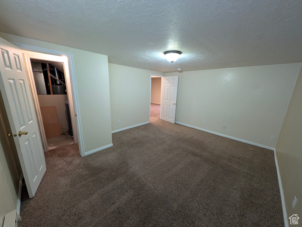 Unfurnished bedroom with dark carpet, a textured ceiling, and a spacious closet