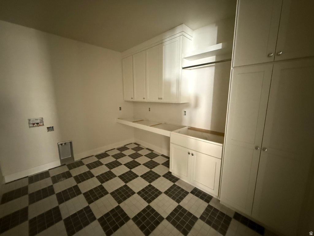 Laundry room with cabinet space and baseboards