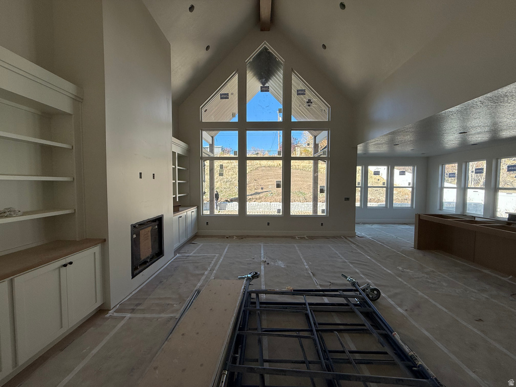 Unfurnished living room with a fireplace, high vaulted ceiling, and beamed ceiling