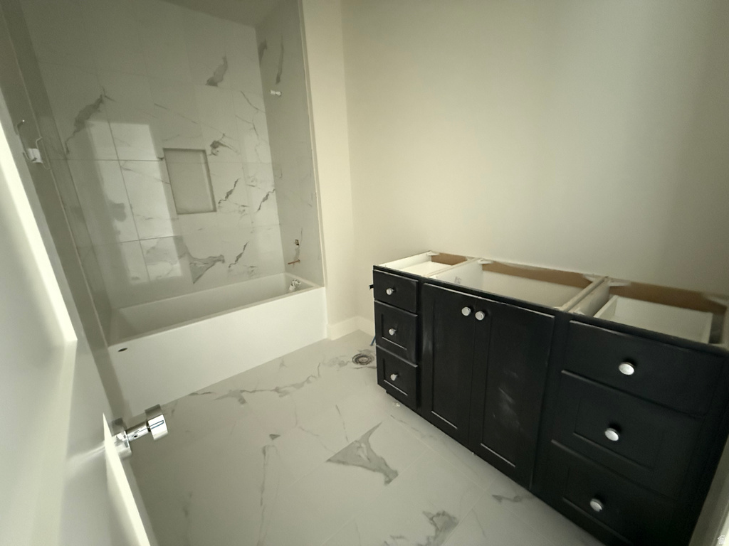 Full bath featuring vanity, light marble finish flooring, and a combined bath / shower with marble appearance