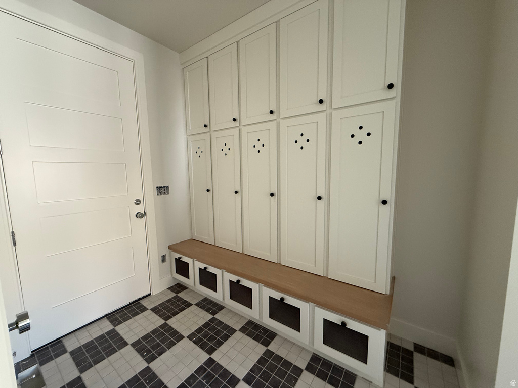 Mudroom with dark tile patterned flooring and baseboards