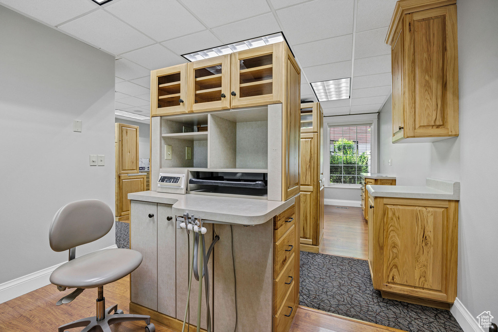 Kitchen featuring glass insert cabinets, light countertops, a paneled ceiling, dark wood-type flooring, and open shelves