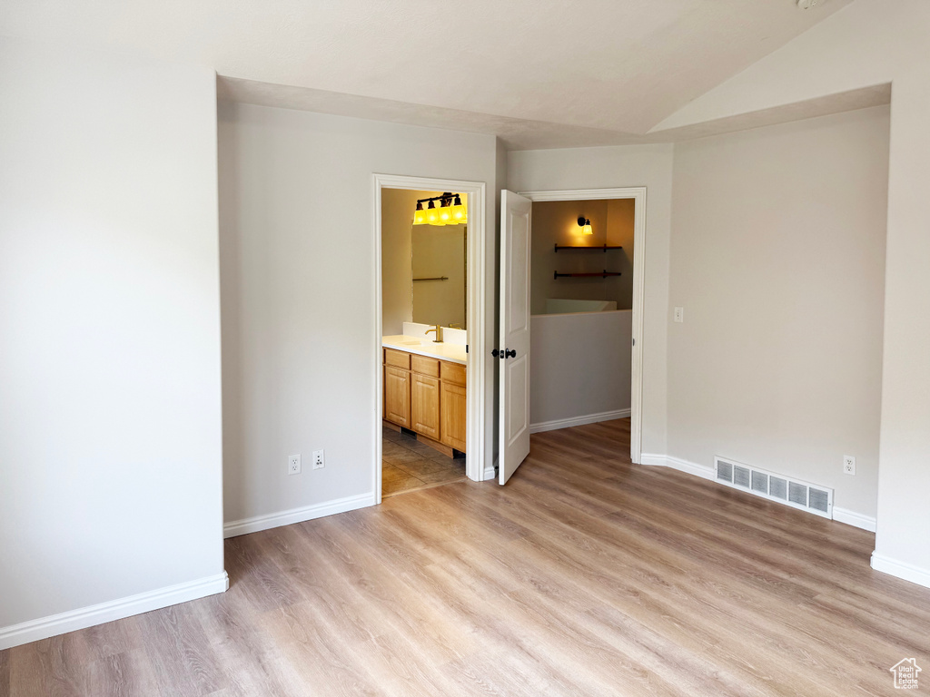 Spare room with light wood-style floors and vaulted ceiling