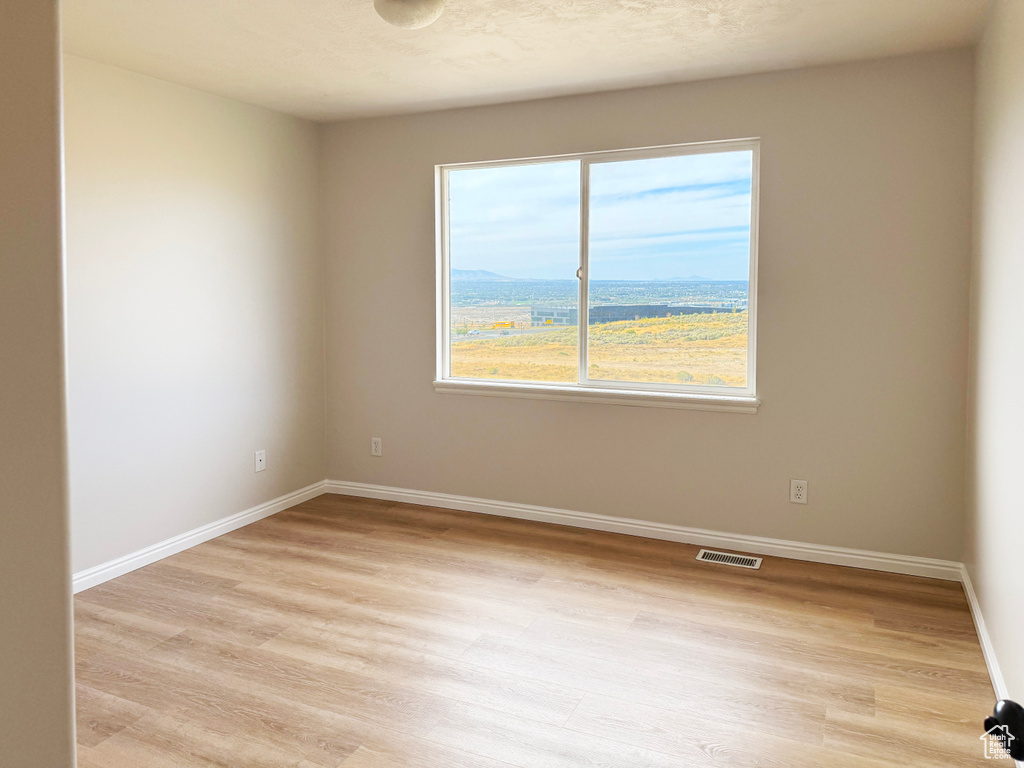 Empty room featuring baseboards and light wood finished floors