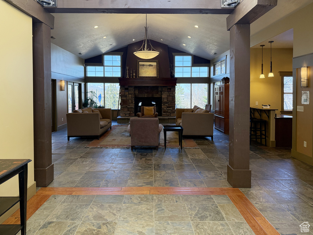 Living area with high vaulted ceiling, stone tile floors, a fireplace, and recessed lighting