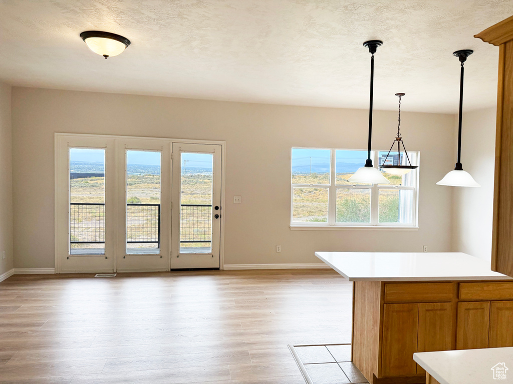Unfurnished dining area featuring light wood-type flooring and a textured ceiling