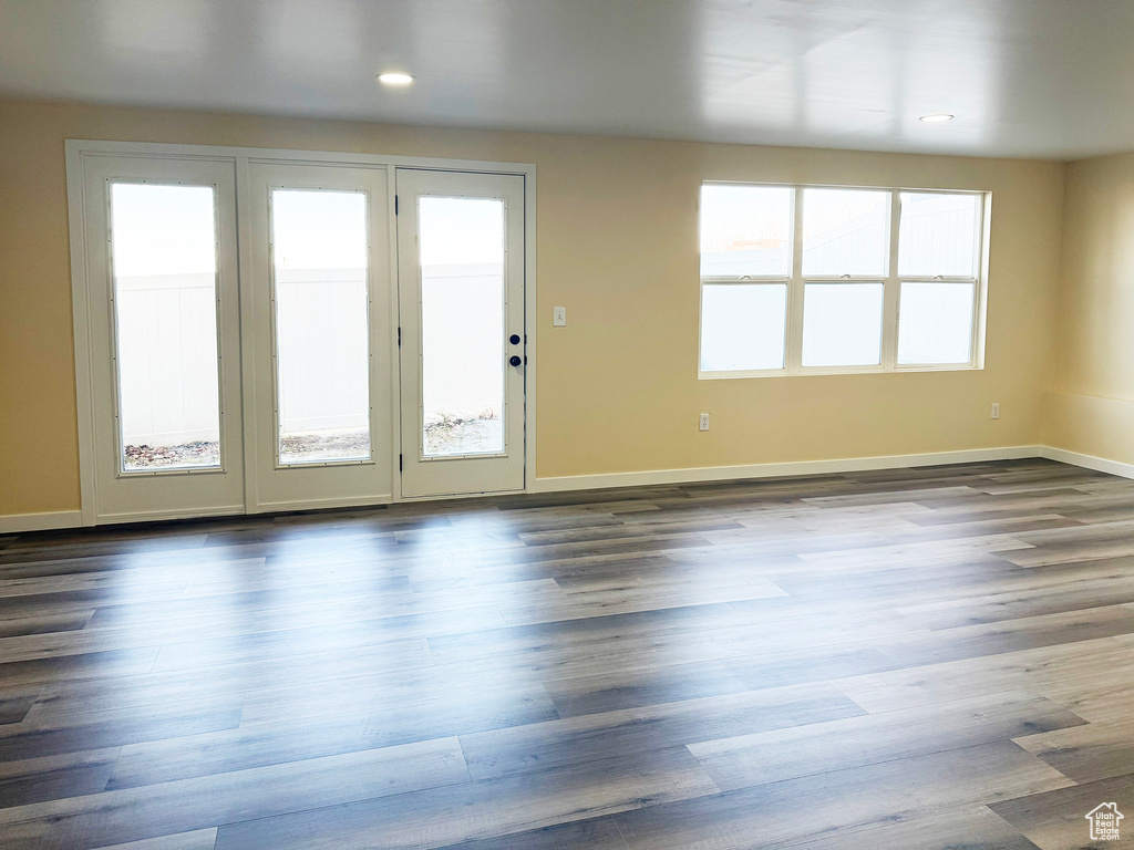 Unfurnished living room with baseboards and dark wood-type flooring