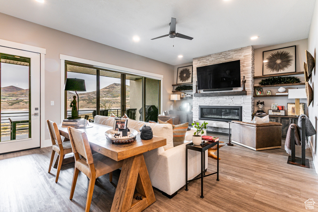 Living area with a stone fireplace, light wood-style flooring, a ceiling fan, and recessed lighting