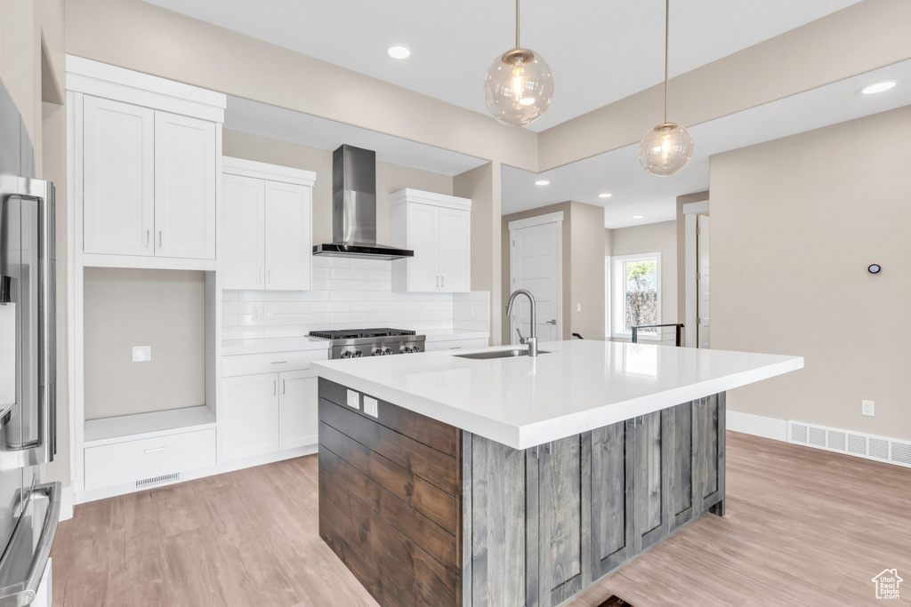 Kitchen with white cabinets, a kitchen island with sink, tasteful backsplash, decorative light fixtures, and recessed lighting