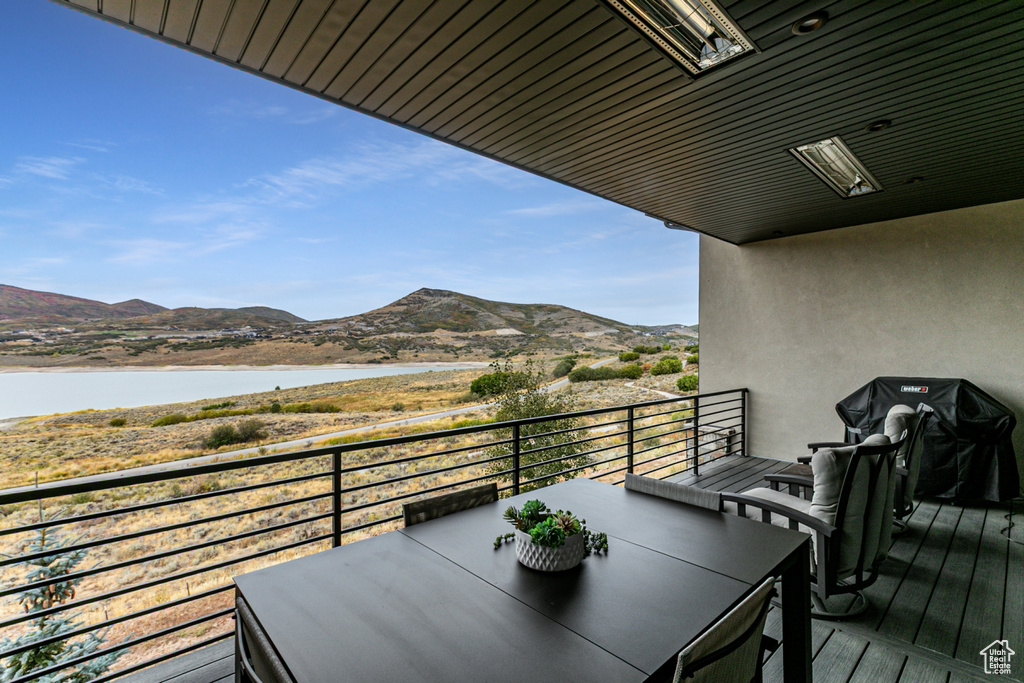 Balcony featuring outdoor dining space, a water and mountain view, and area for grilling