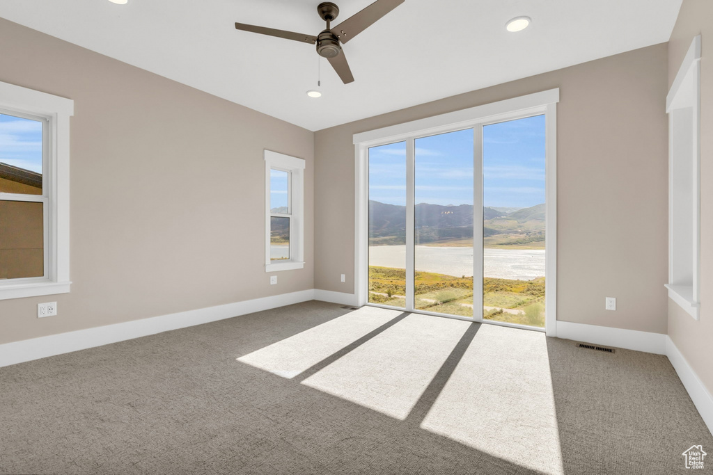 Empty room with a mountain view, light carpet, ceiling fan, and recessed lighting