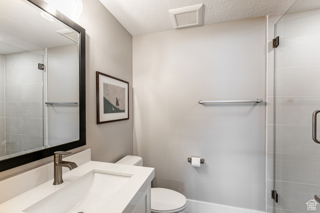 Full bath with vanity, a textured ceiling, and a stall shower