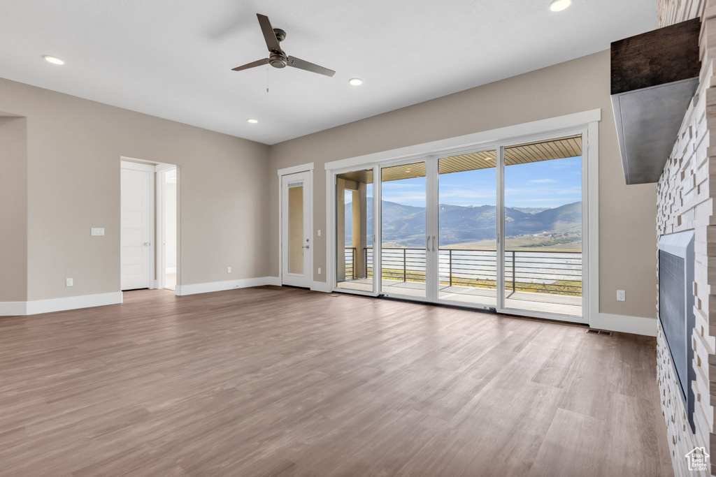 Unfurnished living room featuring a fireplace, light wood finished floors, a ceiling fan, and recessed lighting