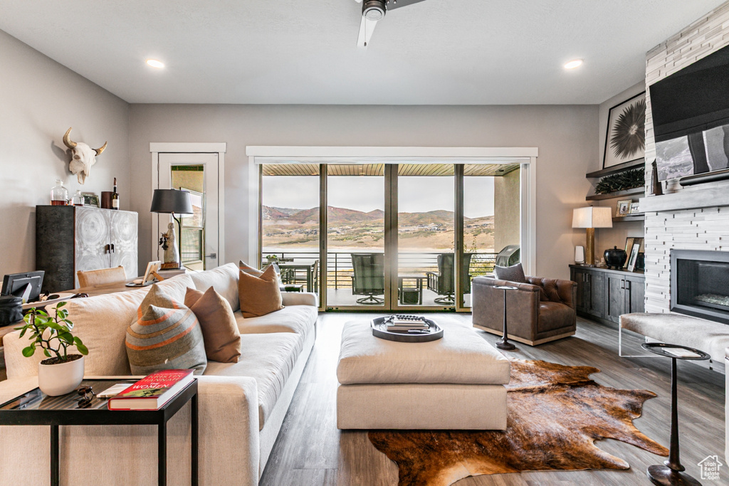 Living room with a stone fireplace, wood finished floors, and recessed lighting