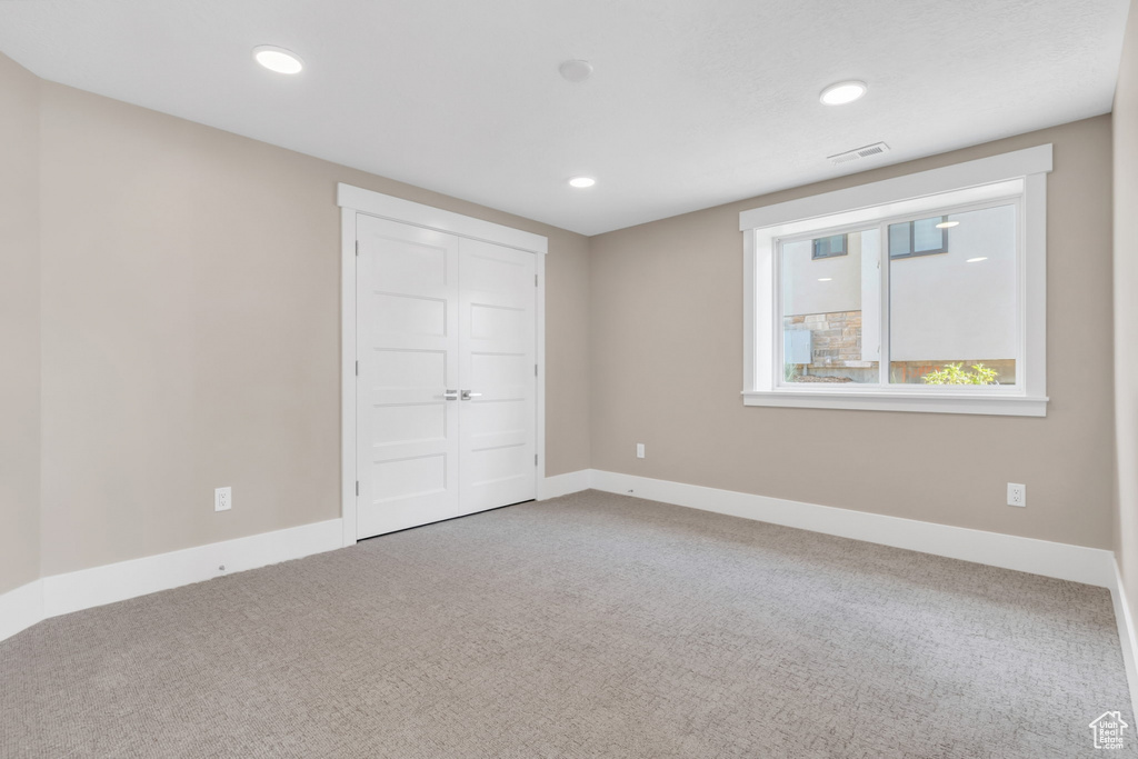 Unfurnished bedroom featuring light carpet, a closet, and recessed lighting