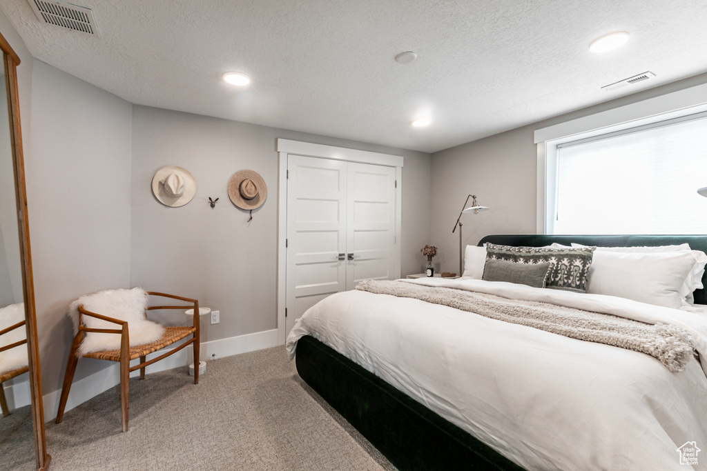 Bedroom with light carpet, a closet, and a textured ceiling