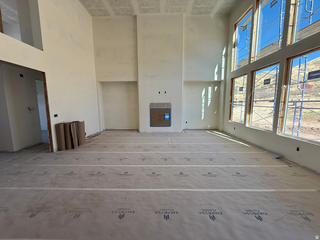 Unfurnished living room featuring a towering ceiling