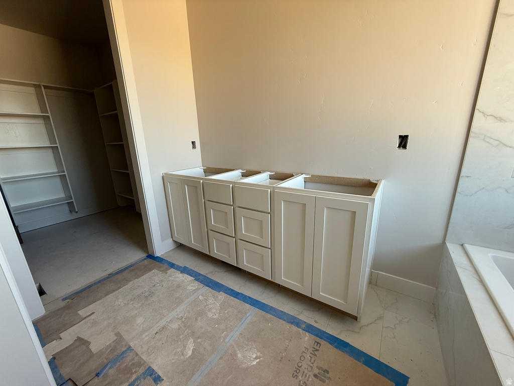 Full bath featuring vanity, a relaxing tiled tub, and a walk in closet