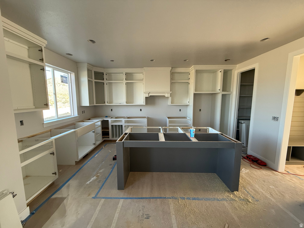 Kitchen featuring a kitchen island, premium range hood, and white cabinetry